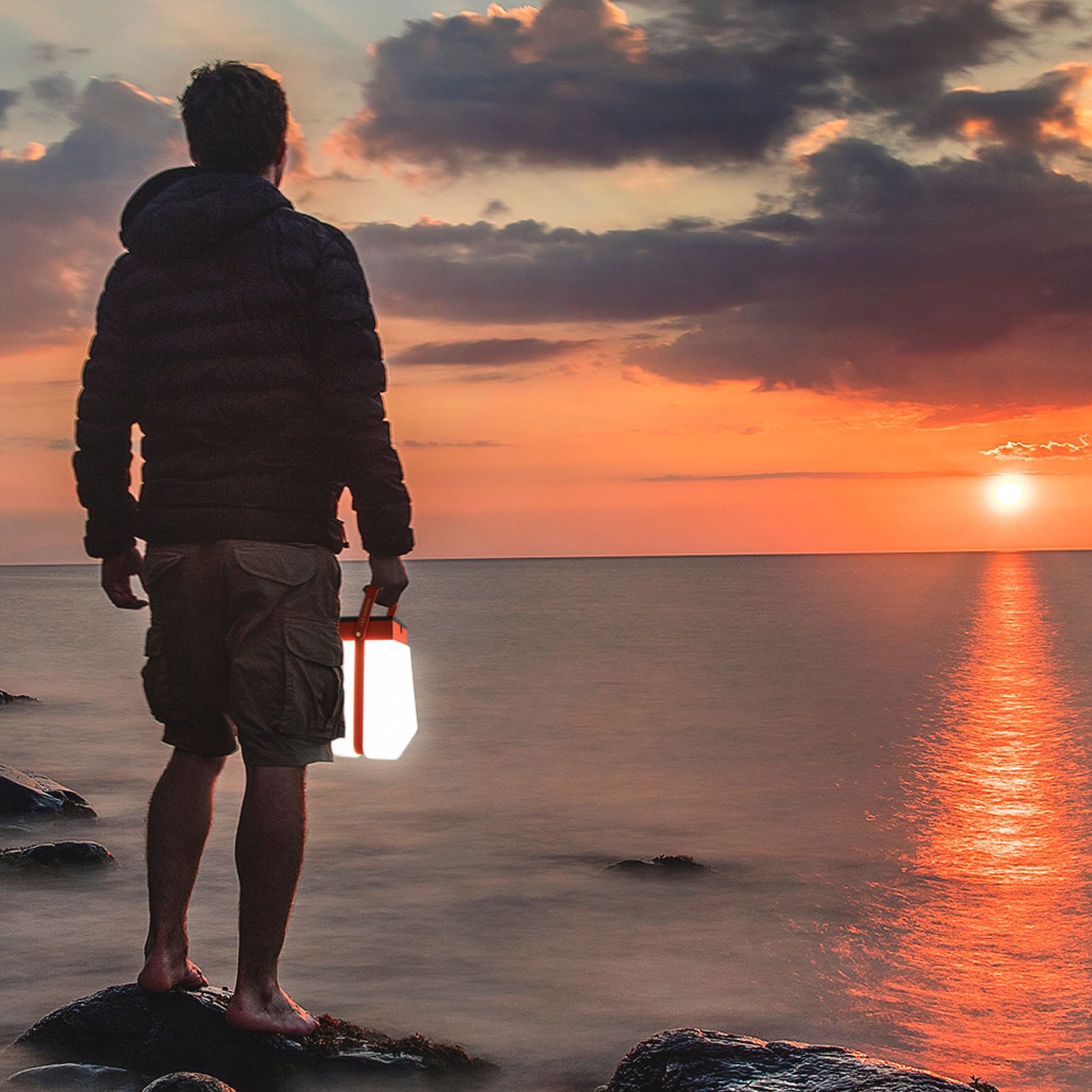 man with bump lantern light up enjoying sunset by the sea