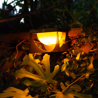 Les Jardins Flow sconce lighting up fence garden in amber mode